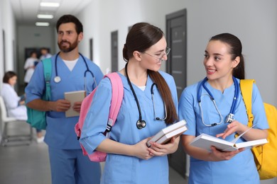 Photo of Smart medical students with books in college hallway, space for text