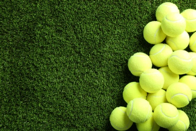 Photo of Heap of tennis balls on green grass, top view. Space for text