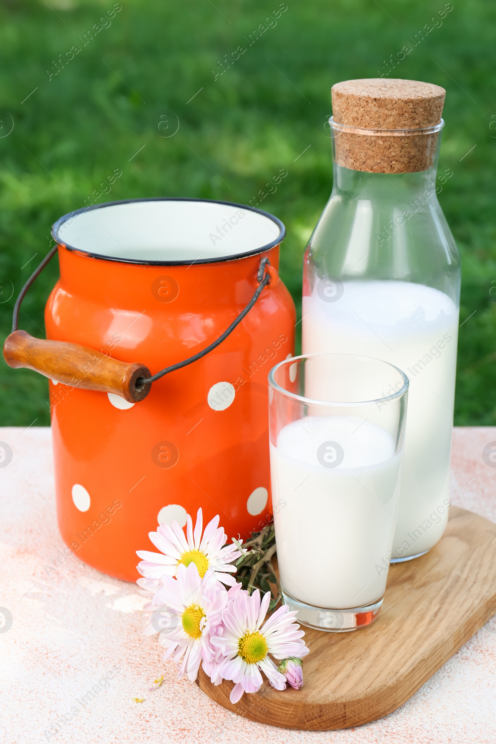 Photo of Tasty fresh milk on color textured table outdoors