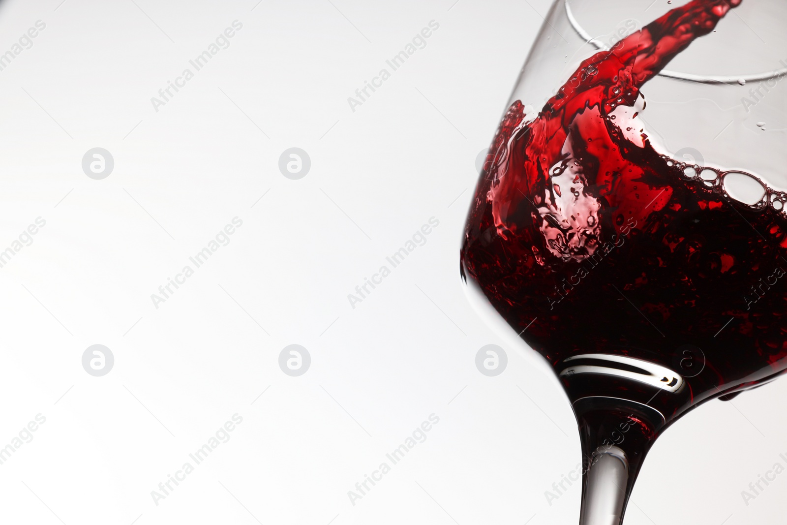 Photo of Pouring tasty red wine in glass on white background, closeup. Space for text