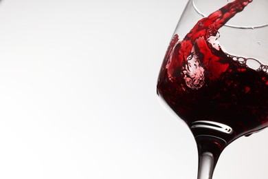 Photo of Pouring tasty red wine in glass on white background, closeup. Space for text