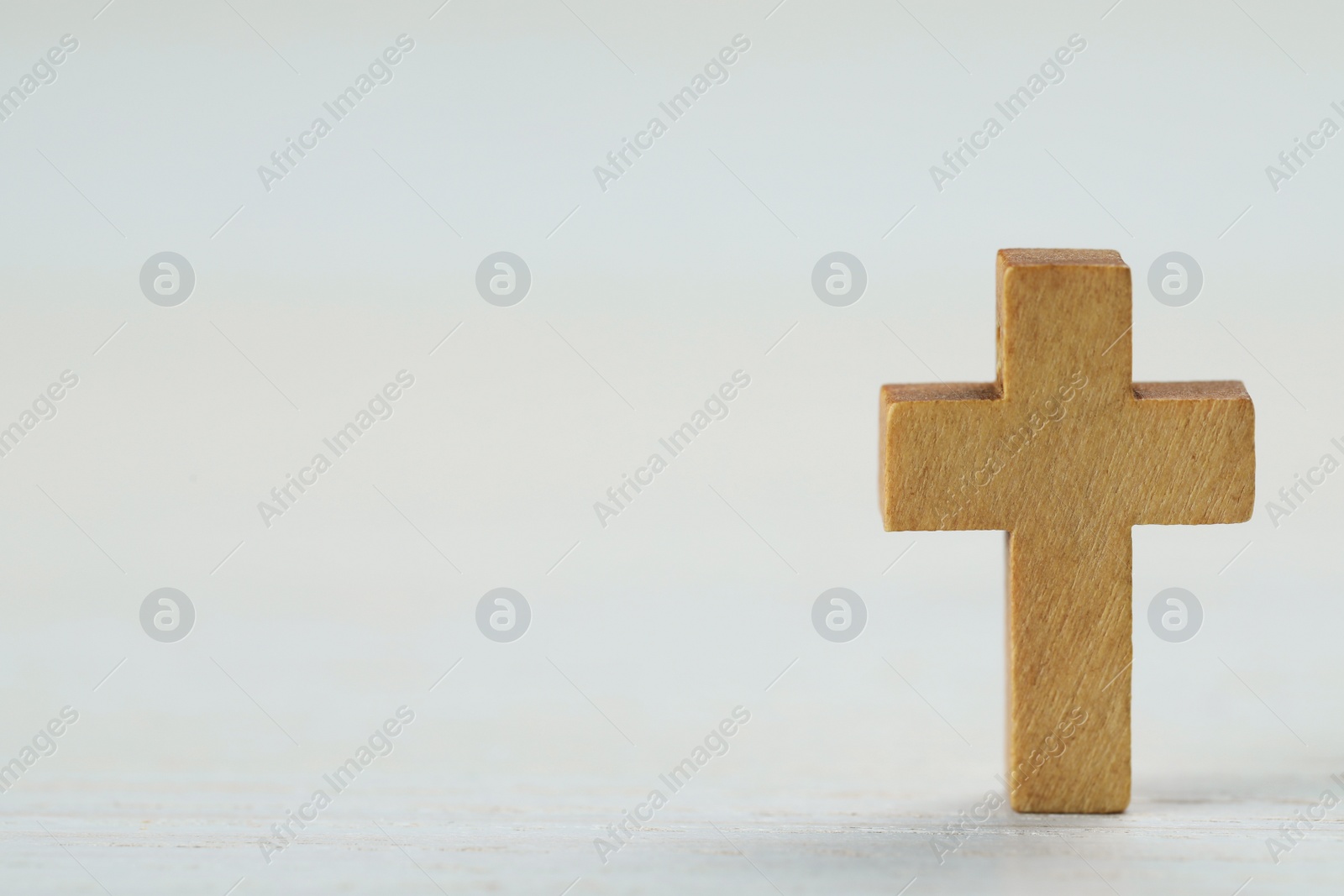 Photo of Wooden Christian cross on white table, space for text