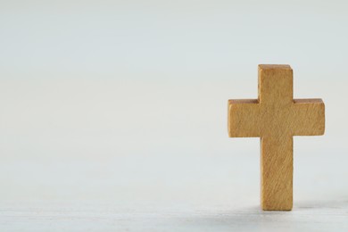 Wooden Christian cross on white table, space for text
