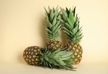 Ripe juicy pineapples on light yellow background