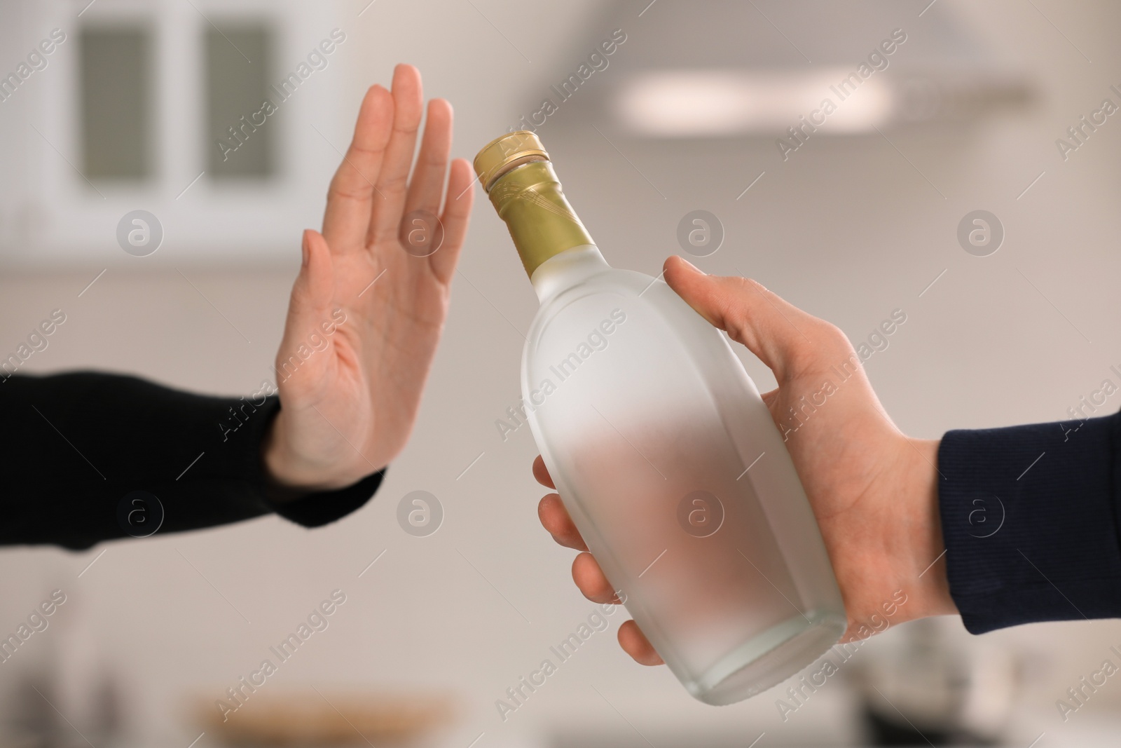 Photo of Woman refusing to drink vodka in kitchen, closeup. Alcohol addiction treatment