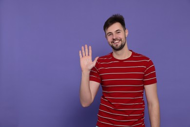 Photo of Man giving high five on purple background. Space for text