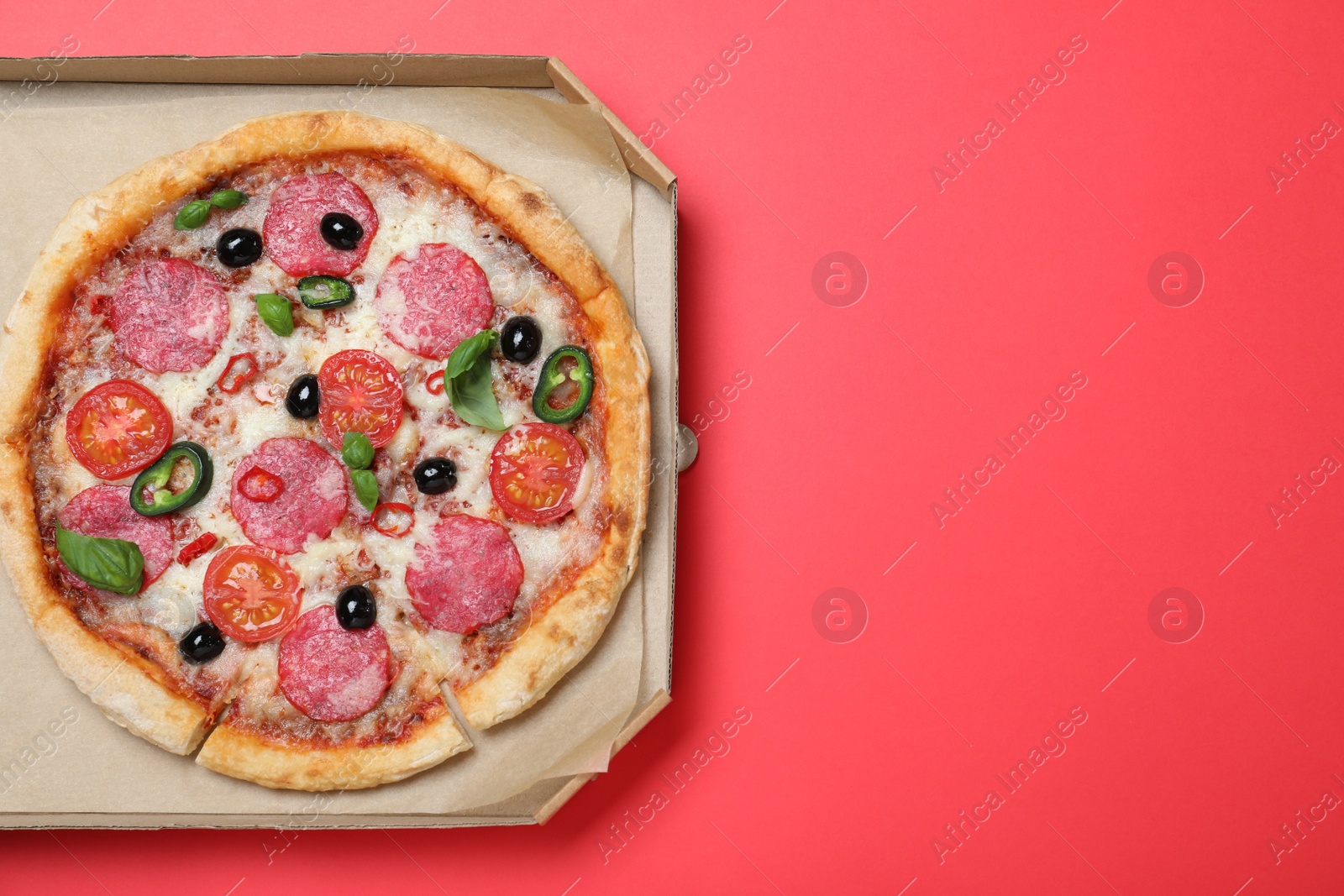 Photo of Delicious pizza Diablo in cardboard box on red background, top view. Space for text