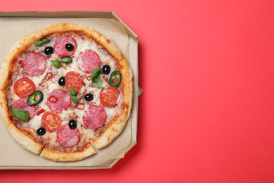 Photo of Delicious pizza Diablo in cardboard box on red background, top view. Space for text