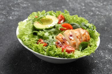 Delicious salad with chicken, cherry tomato and avocado on grey textured table, closeup