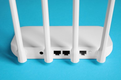 Photo of New white Wi-Fi router on blue background, back view