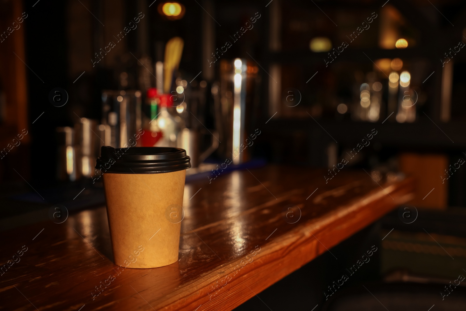 Photo of Paper coffee cup on wooden table in cafe. Space for text