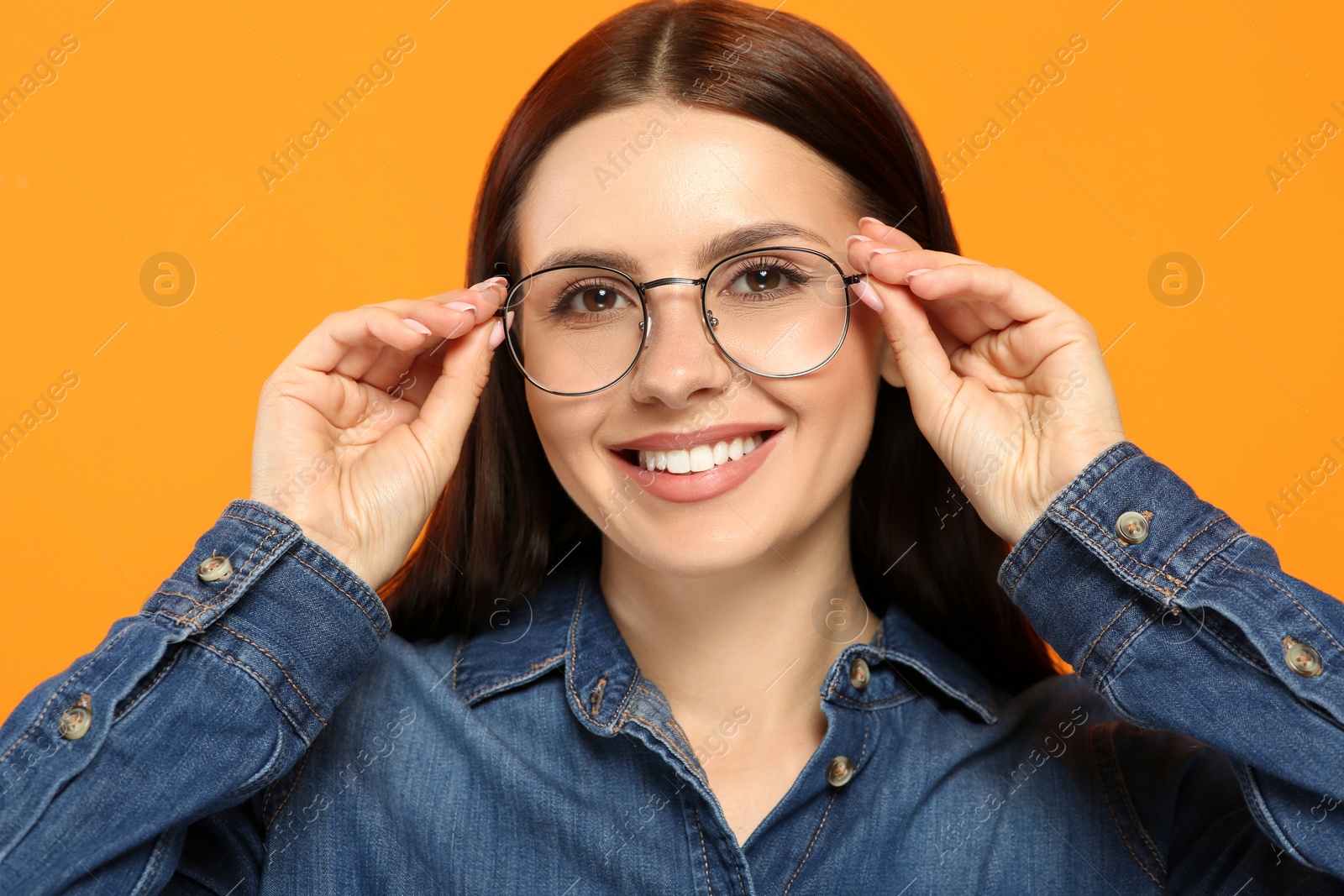 Photo of Portrait of smiling woman in stylish eyeglasses on orange background