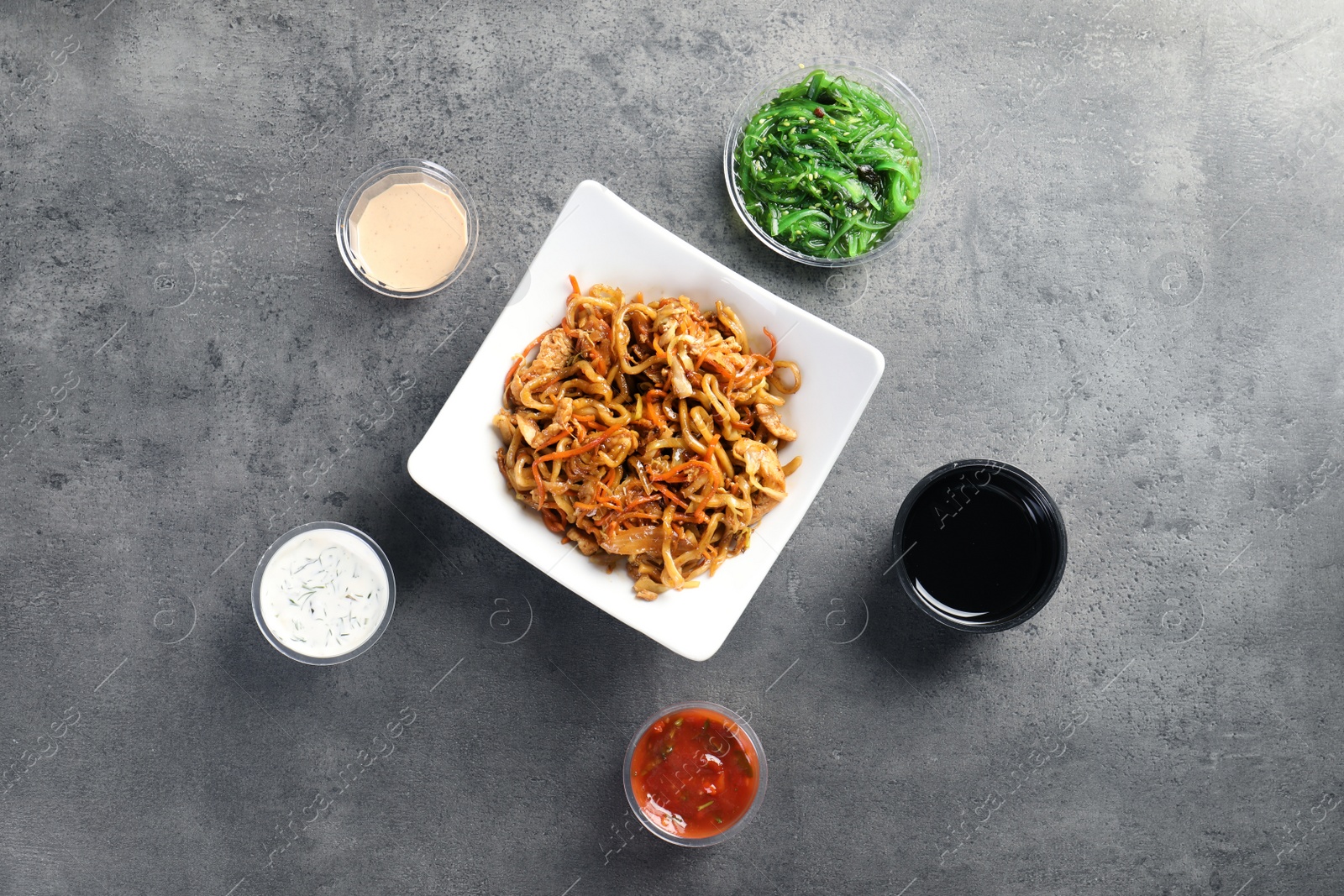 Photo of Flat lay composition with Chinese noodles on grey table. Food delivery