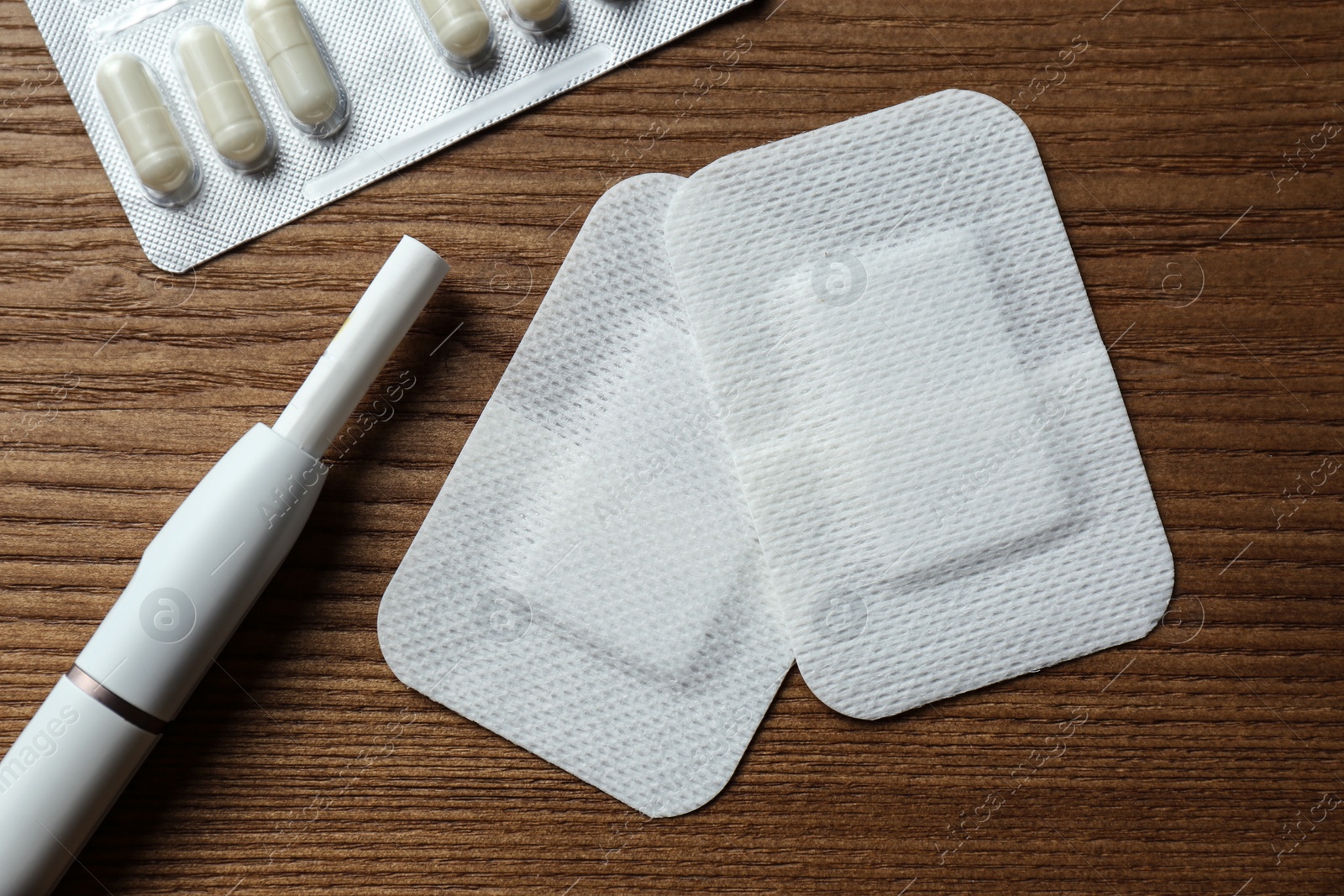 Photo of Nicotine patches, pills and electronic cigarette on wooden table, flat lay