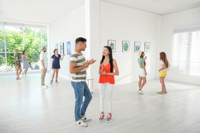 Happy couple with glasses of champagne at exhibition in art gallery