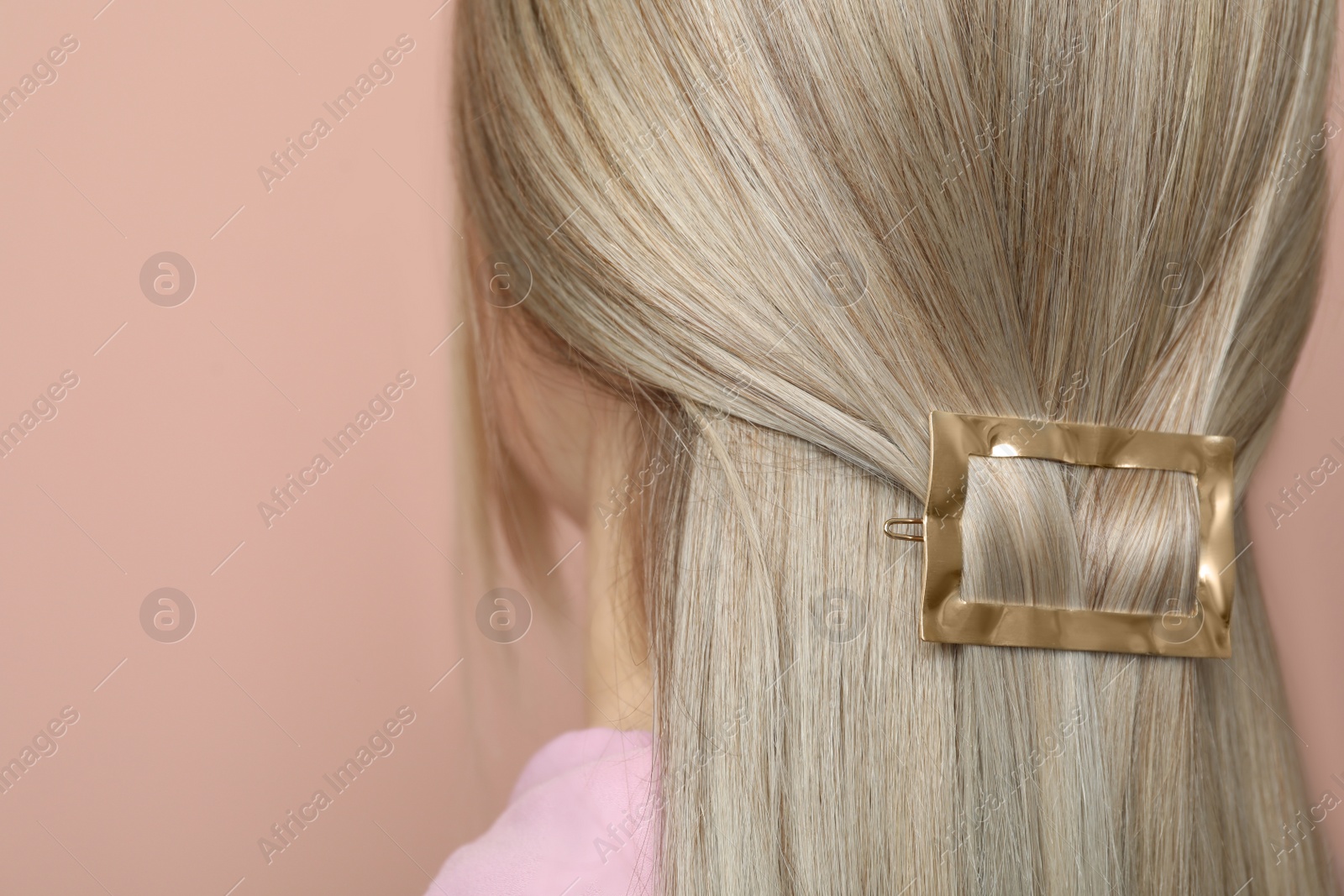 Photo of Young woman with beautiful gold hair clip on pink background, closeup