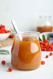 Photo of Delicious rowan jam in glass jar on white wooden table