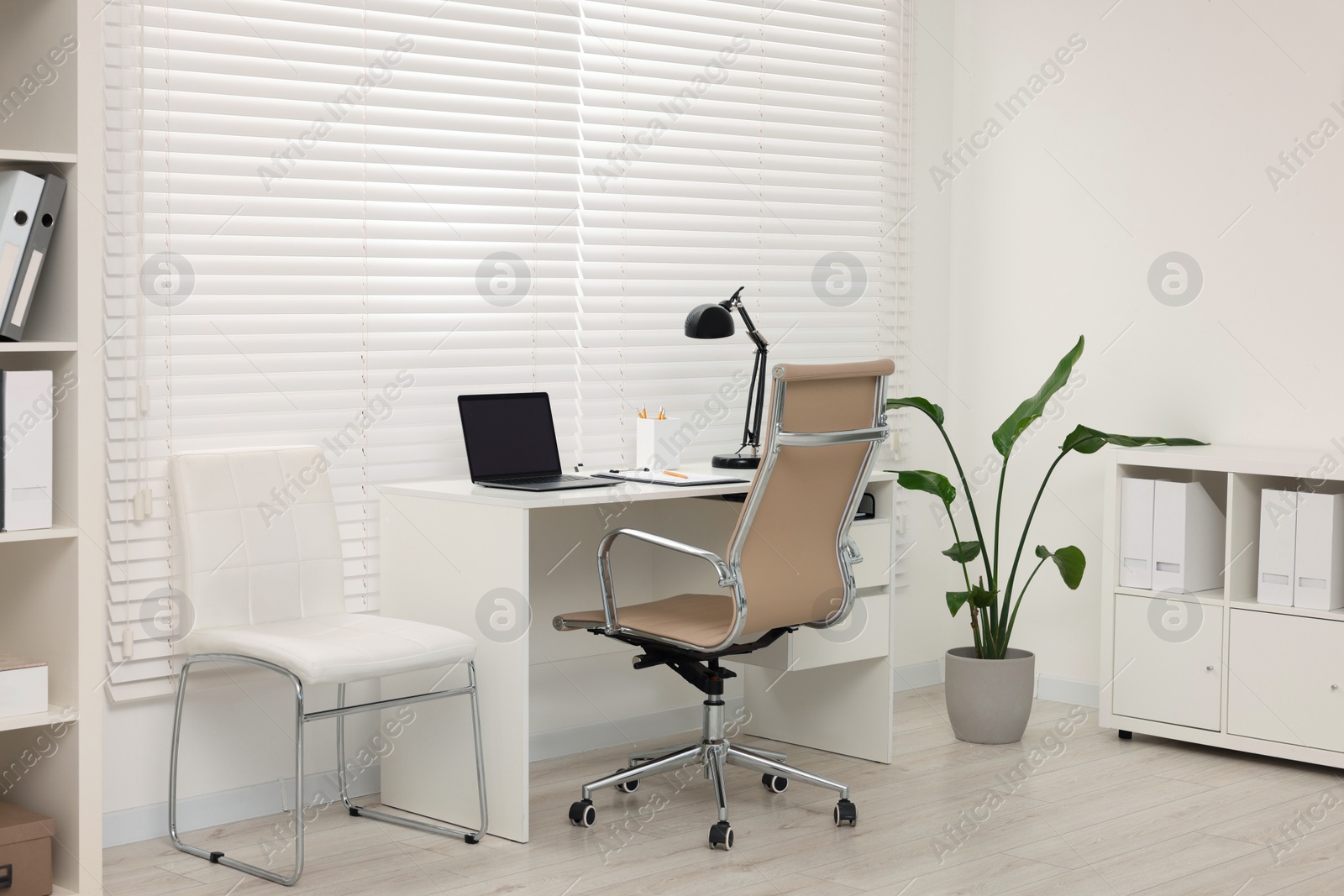 Photo of Doctor's workplace. Chairs, laptop and clipboard on table in clinic