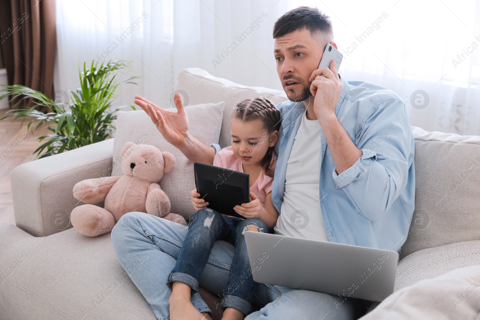 Photo of Overwhelmed man combining parenting and work at home