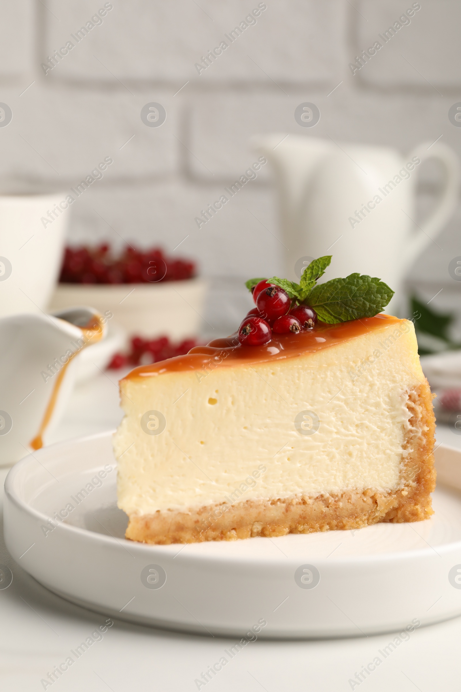 Photo of Piece of delicious caramel cheesecake with red currants and mint served on white marble table