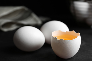 Photo of Fresh raw chicken eggs on black table, closeup