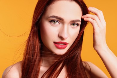 Photo of Beautiful woman with red dyed hair on orange background