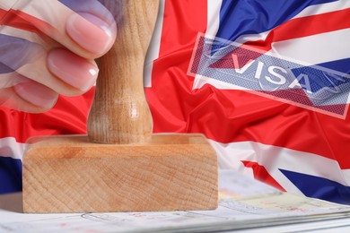 Image of Multiple exposure of woman stamping visa page in passport and flag of Great Britain, closeup