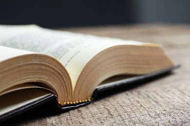 Photo of Open hardcover Bible on wooden table, closeup