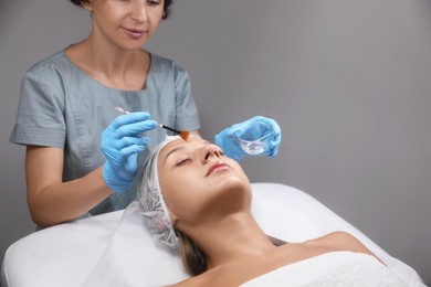 Cosmetologist applying chemical peel product on client's face in salon