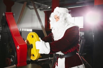 Young Santa Claus with weight plate in modern gym