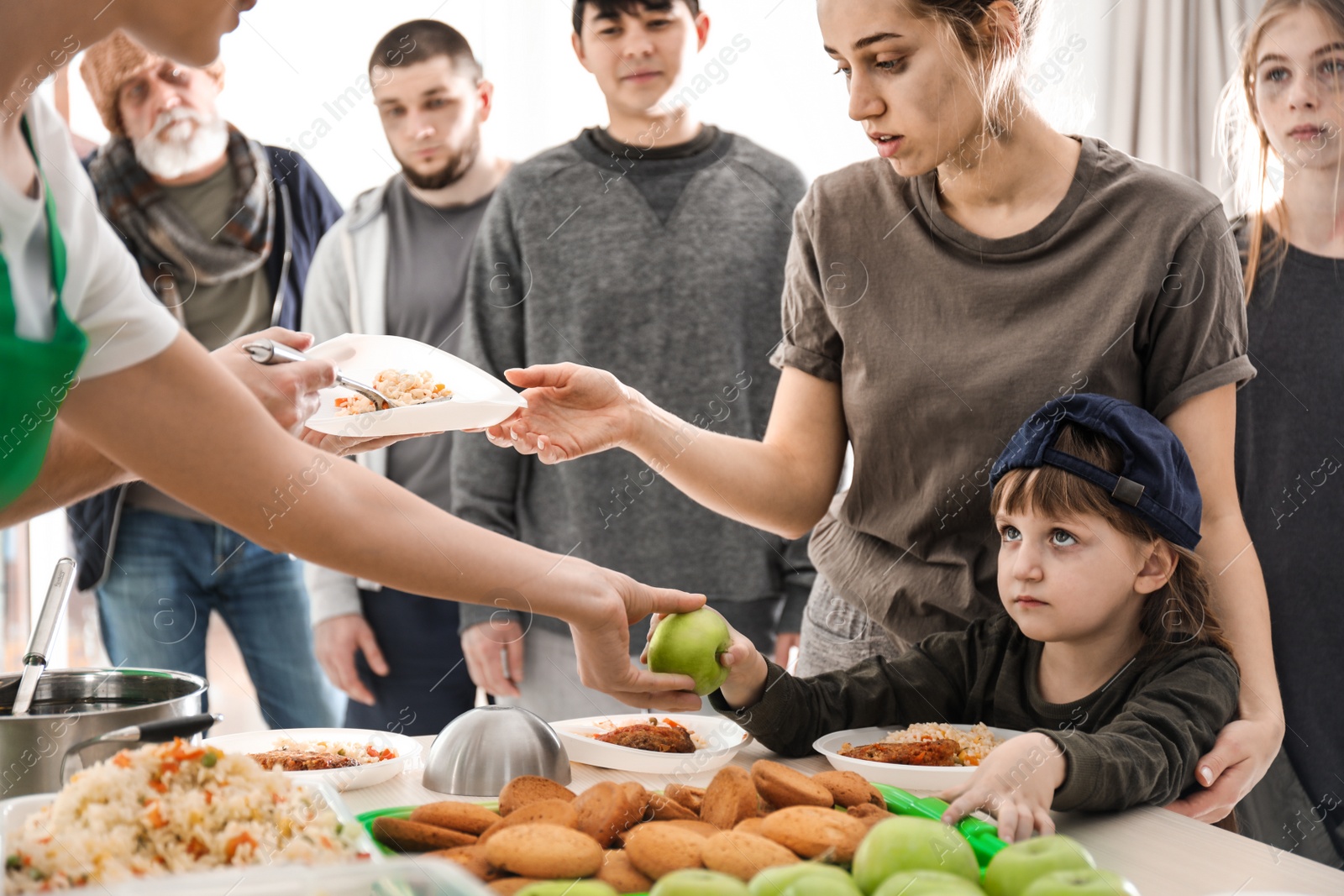 Photo of Poor people receiving food from volunteers indoors