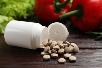 Dietary supplements. Overturned bottle, pills and food products on wooden table, closeup