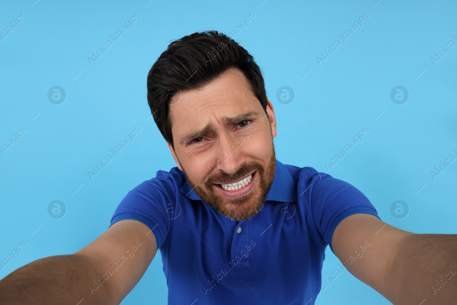 Photo of Emotional man taking selfie on light blue background