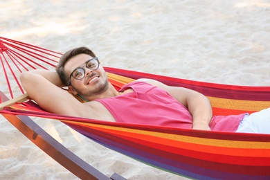 Young man resting in colorful hammock at seaside