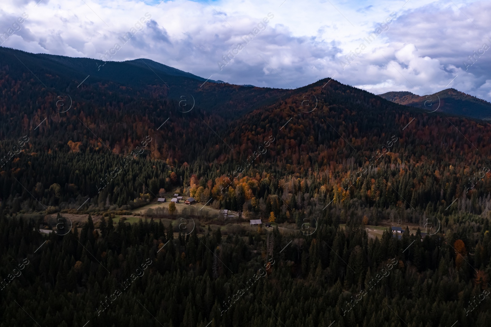 Image of Aerial view of mountain forest and village on autumn day