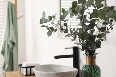 Photo of Beautiful eucalyptus branches near vessel sink in bathroom, space for text. Interior design