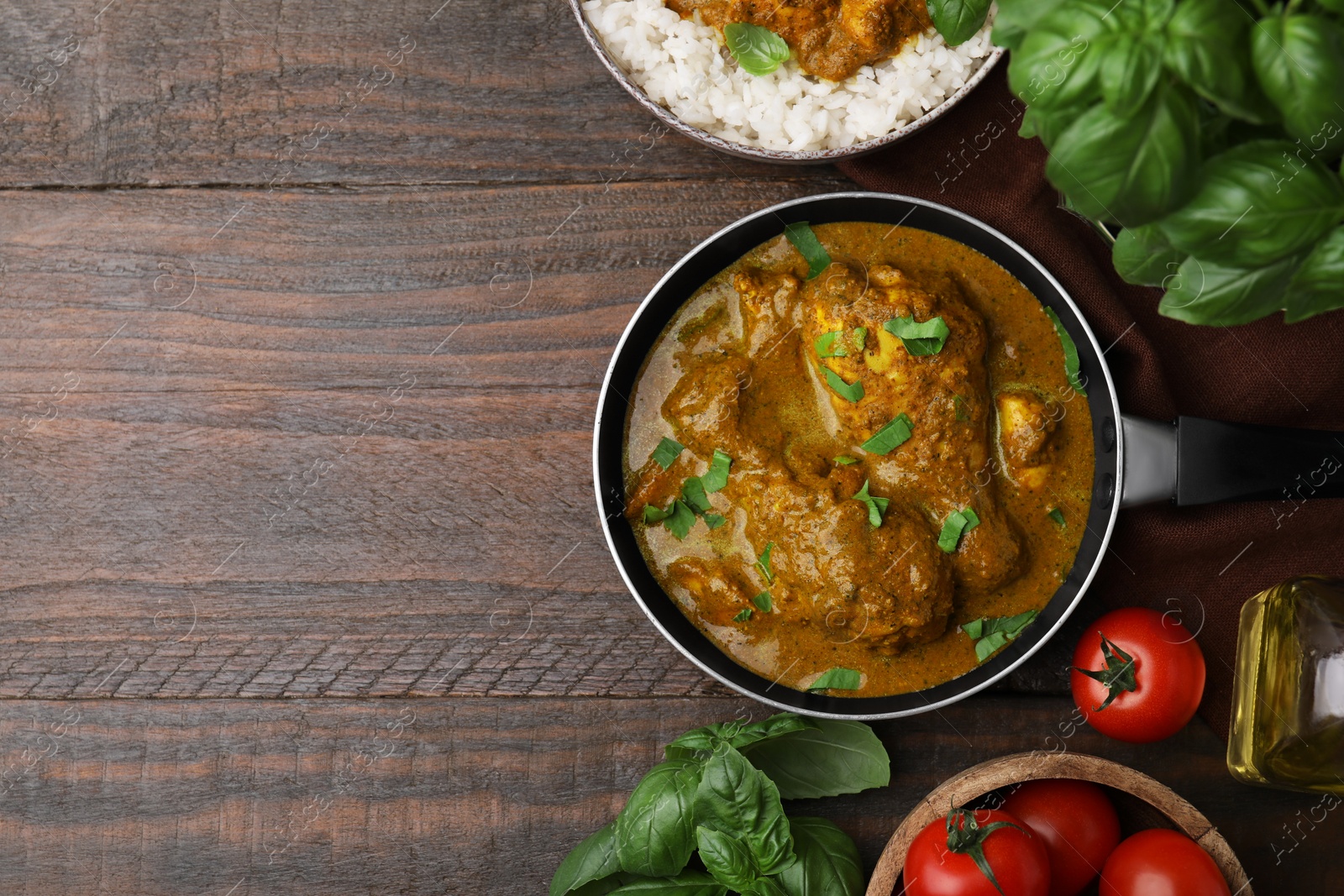 Photo of Delicious chicken with curry sauce and ingredients on wooden table, flat lay. Space for text