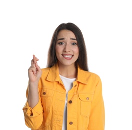 Photo of Nervous young woman holding fingers crossed on white background. Superstition for good luck 