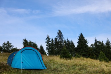 Photo of Blue camping tent on green grass near forest, space for text