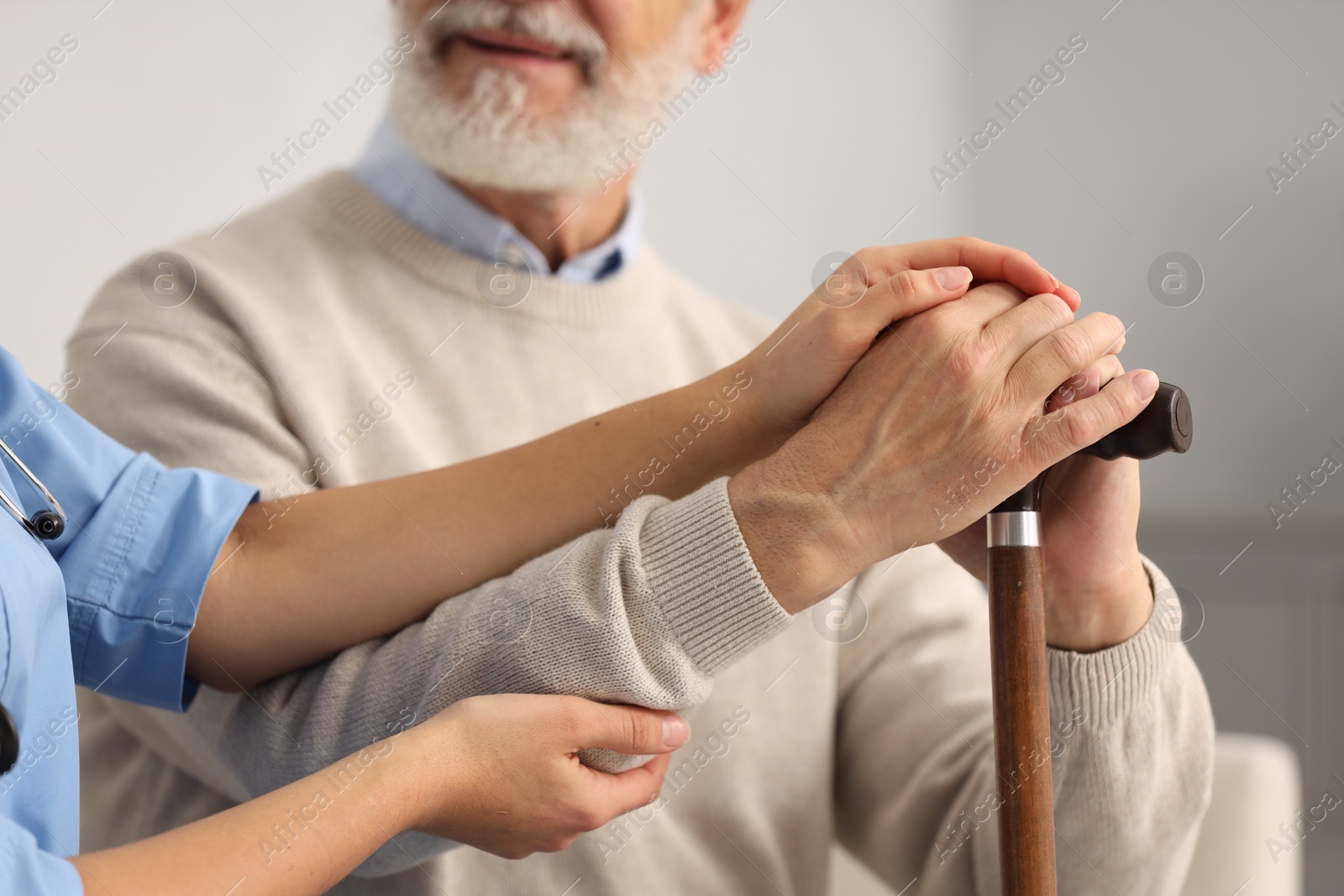 Photo of Nurse supporting elderly patient indoors, closeup view