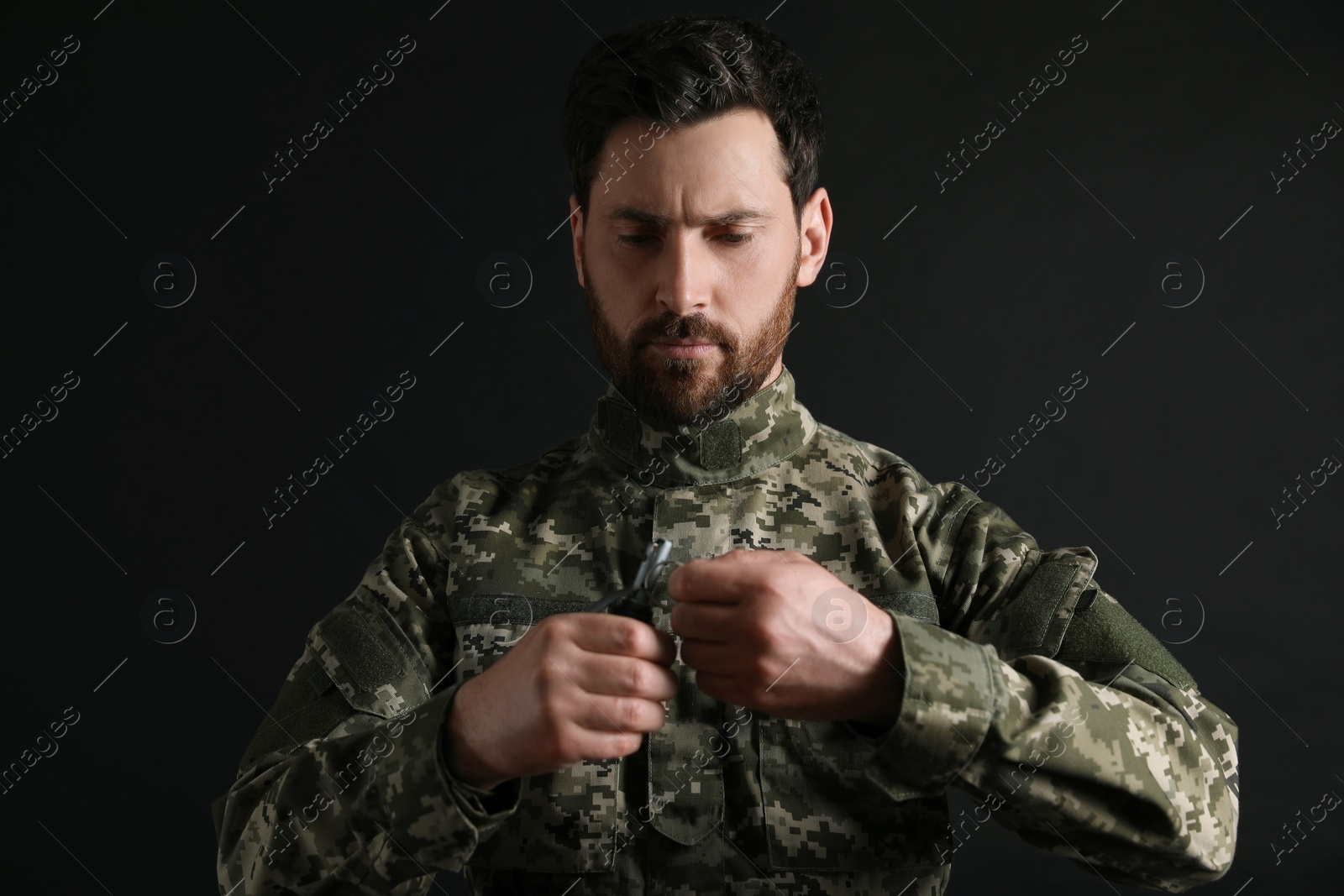 Photo of Soldier pulling safety pin out of hand grenade on black background. Military service