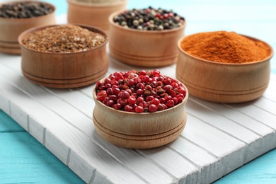 Photo of Bowls with different kinds of pepper on white wooden board