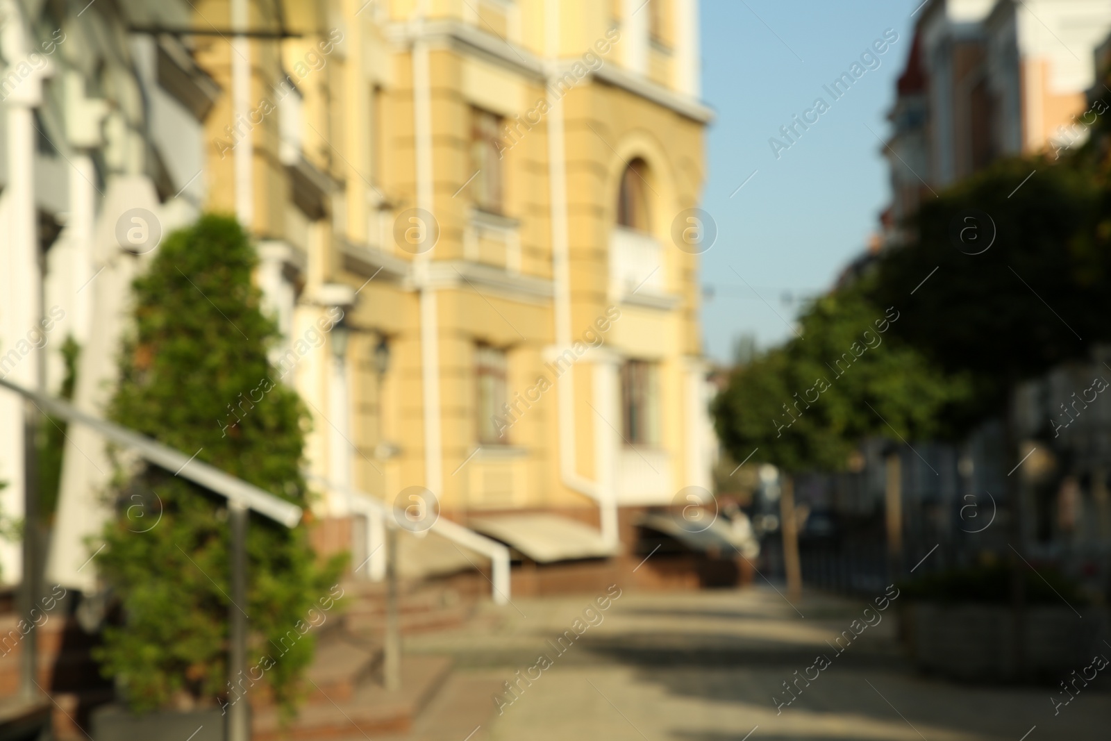Photo of Blurred view of quiet city street with buildings on sunny day