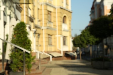 Blurred view of quiet city street with buildings on sunny day