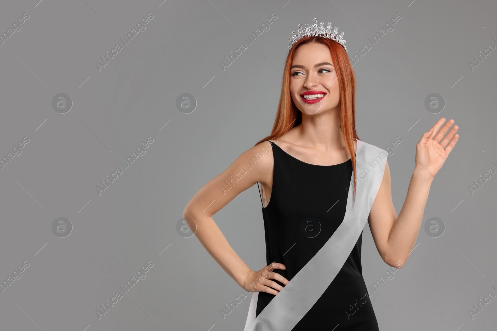Photo of Beautiful young woman with tiara and ribbon in dress on light grey background, space for text. Beauty contest
