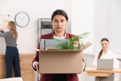 Photo of Unemployment problem. Woman with box of personal belongings in office