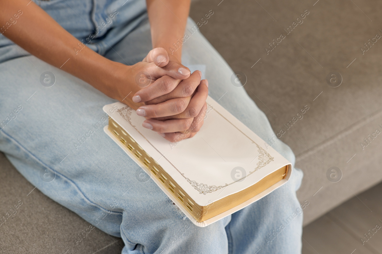 Photo of Religious woman with Bible praying indoors, closeup