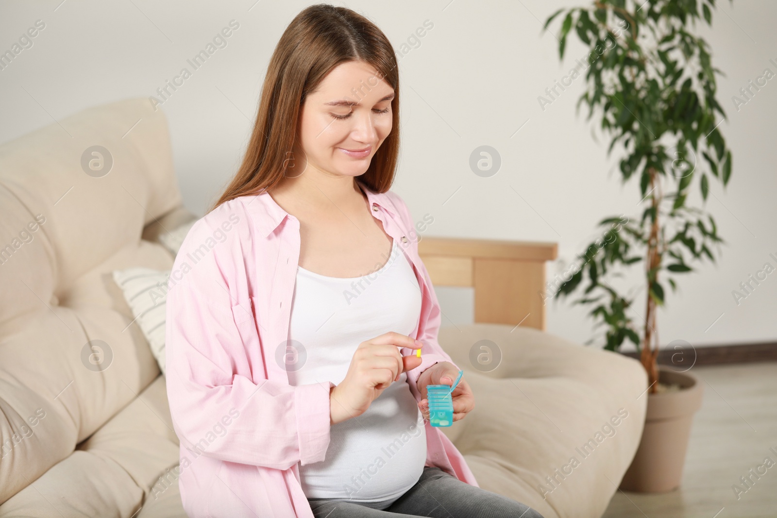 Photo of Beautiful pregnant woman holding pill at home