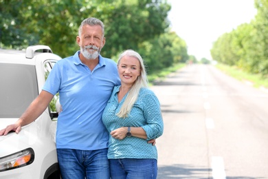 Photo of Happy senior couple posing near car outdoors