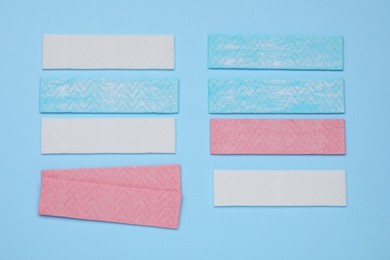 Sticks of tasty chewing gum on light blue background, flat lay